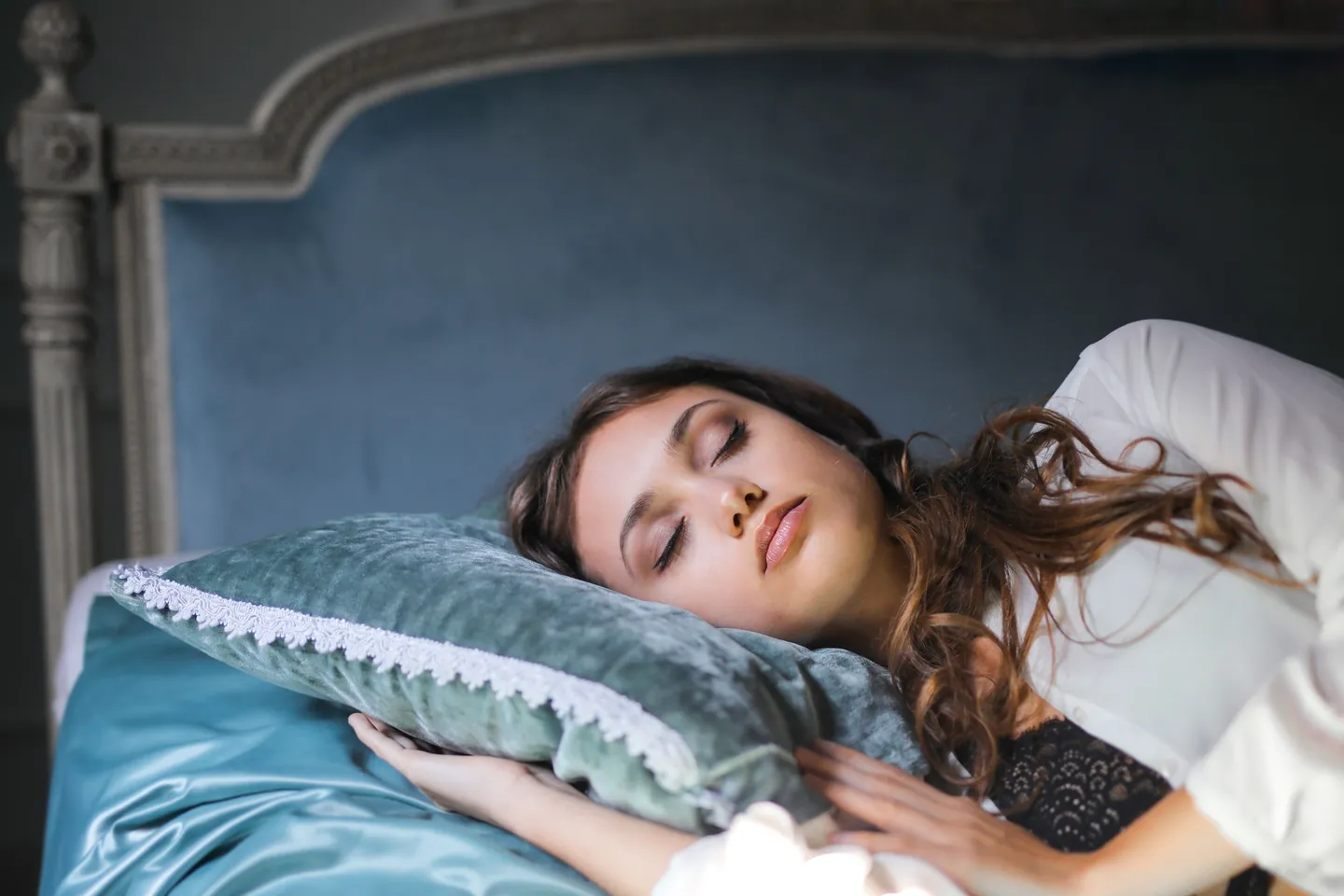 Woman in a pale robe resting on a blue cushion in natural light